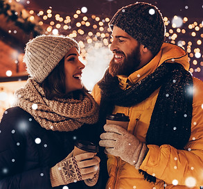 Couple enjoying a hot drink surrounded in snowfall at Sip n' Shop event 