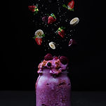 a wild berry smoothie in a mason jar with fruit falling from above down into the jar at Yog N’ Shake