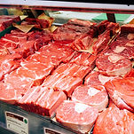 Several cuts of fresh meat in a cooler display at Charles' Quality Meats